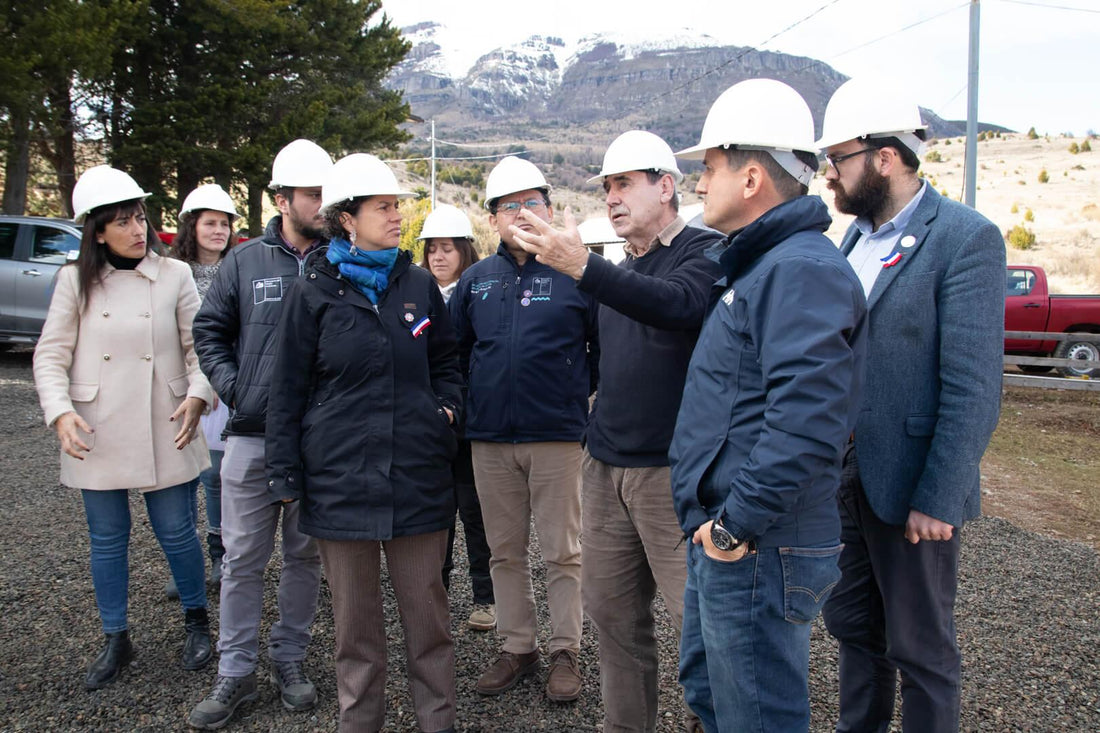 Grupo de personas con cascos blancos en exterior montañoso, discutiendo en sitio de construcción